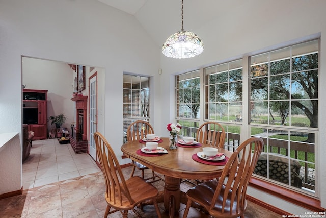 tiled dining area featuring high vaulted ceiling