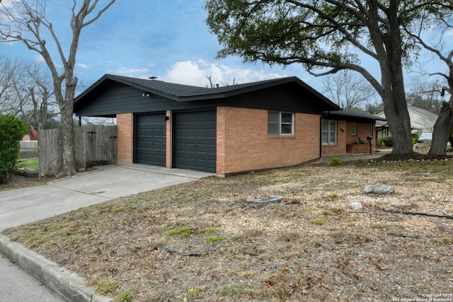 view of home's exterior featuring brick siding, fence, driveway, and an attached garage