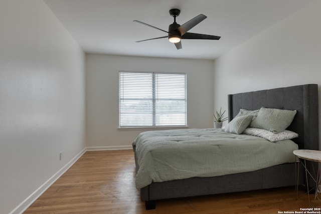 bedroom with a ceiling fan, baseboards, and wood finished floors