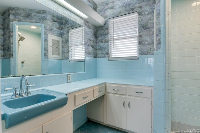 bathroom with tile patterned floors, a tile shower, vanity, and wallpapered walls