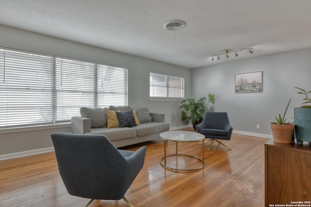 living room with light wood finished floors, baseboards, and visible vents