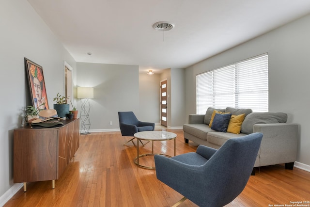 living area with light wood finished floors, baseboards, and visible vents