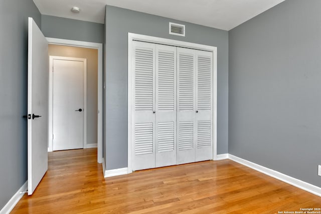 unfurnished bedroom with a closet, visible vents, light wood-style flooring, and baseboards