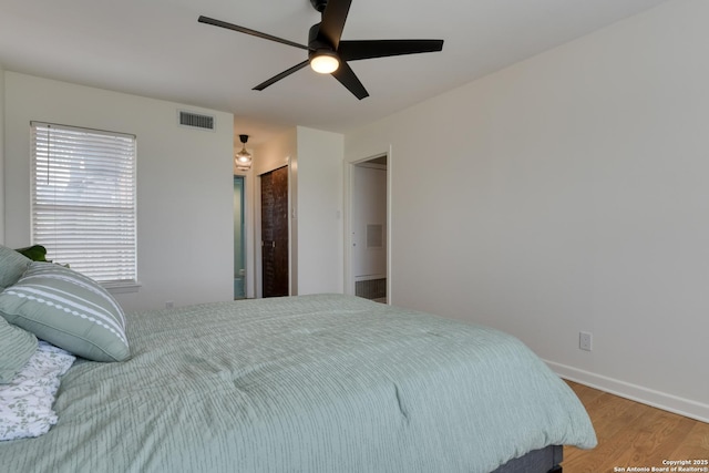 bedroom featuring baseboards, wood finished floors, visible vents, and a ceiling fan