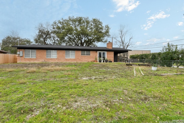 view of front of house with a chimney, a front yard, and fence private yard