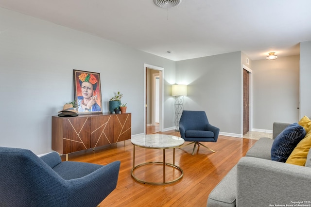 living room featuring wood finished floors, visible vents, and baseboards