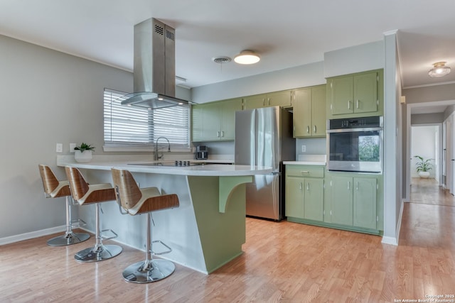 kitchen featuring stainless steel appliances, island range hood, visible vents, and green cabinetry