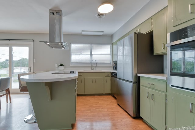 kitchen featuring light countertops, visible vents, green cabinets, appliances with stainless steel finishes, and island range hood