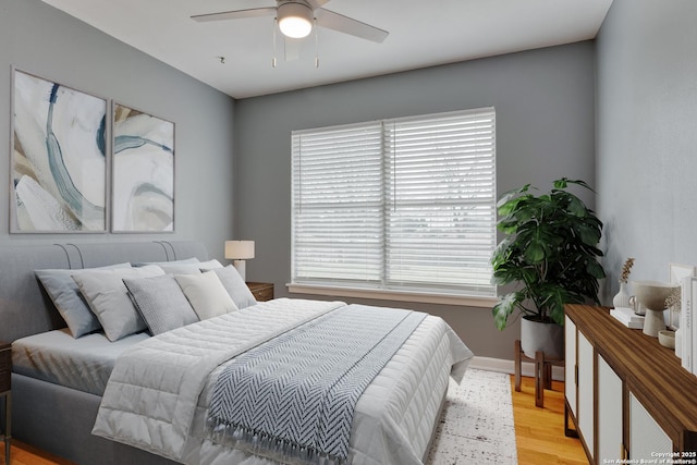 bedroom with a ceiling fan, multiple windows, light wood-style flooring, and baseboards