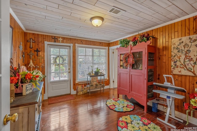 interior space with dark hardwood / wood-style flooring, wood ceiling, ornamental molding, and wood walls