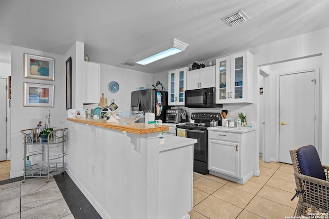 kitchen with light tile patterned flooring, white cabinets, kitchen peninsula, and black appliances