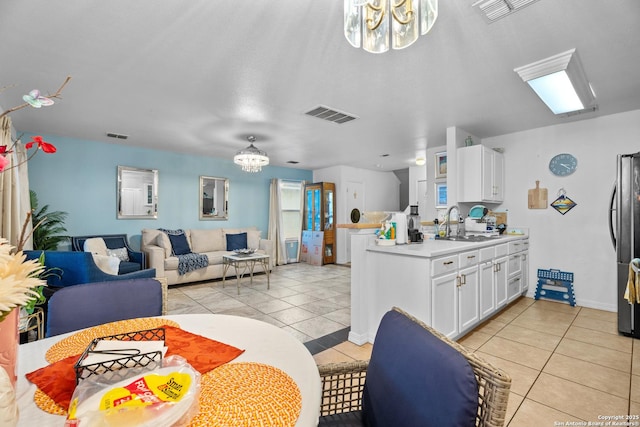 kitchen featuring light tile patterned flooring, sink, white cabinets, and an inviting chandelier