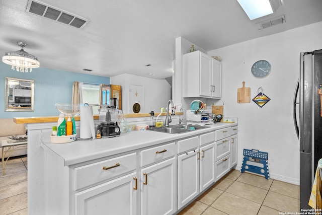 kitchen featuring black fridge, kitchen peninsula, sink, and white cabinets