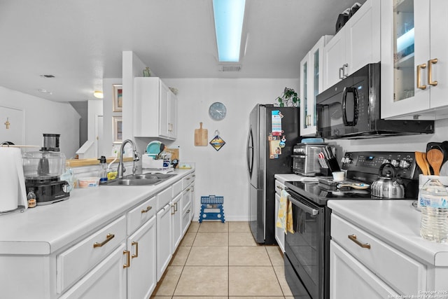 kitchen with sink, light tile patterned floors, white cabinets, and black appliances