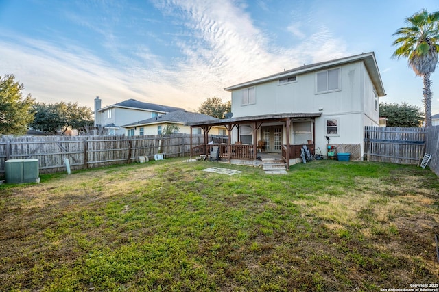 back house at dusk with a yard and a deck