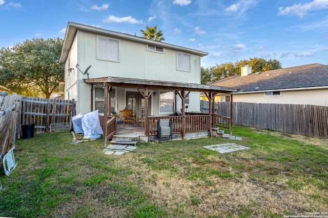 back of property featuring a wooden deck and a lawn