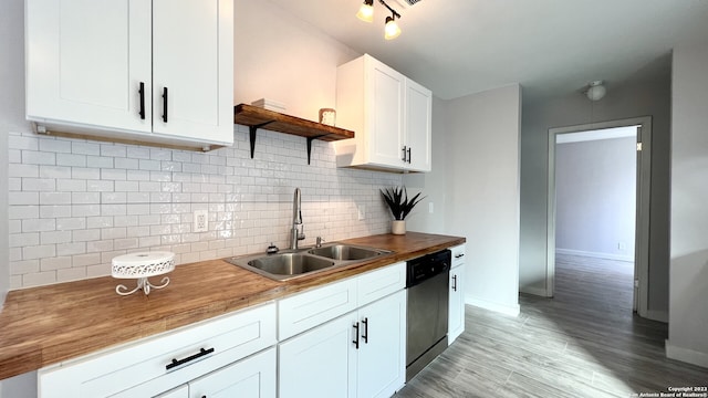 kitchen with sink, wooden counters, dishwasher, white cabinetry, and decorative backsplash