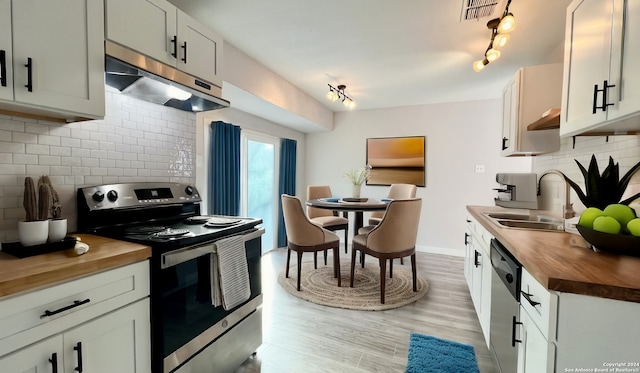 kitchen with wood counters, sink, white cabinetry, and stainless steel appliances