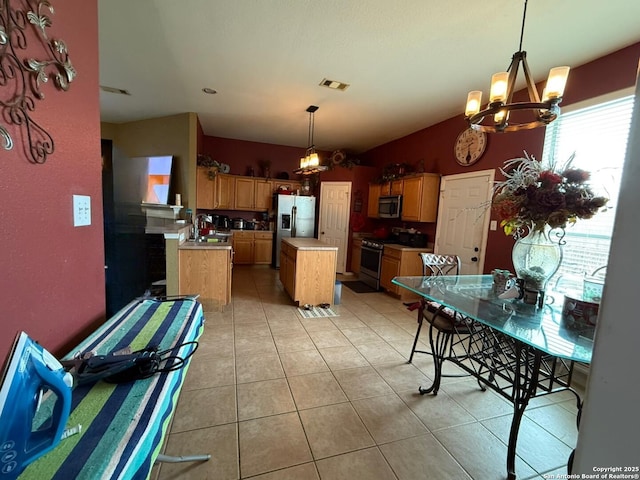 kitchen with pendant lighting, an inviting chandelier, stainless steel appliances, a center island, and light tile patterned flooring