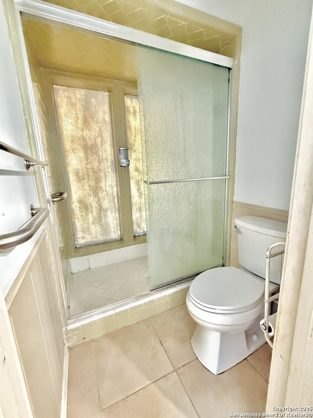 bathroom featuring walk in shower, tile patterned floors, and toilet