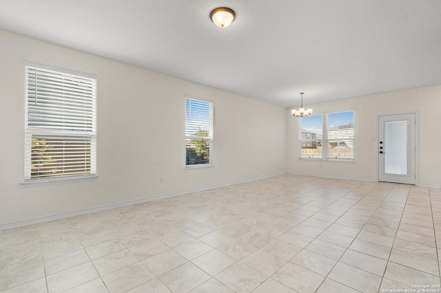 tiled spare room featuring a chandelier