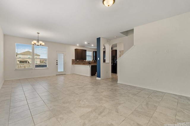 unfurnished living room featuring a chandelier