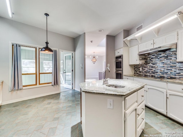 kitchen featuring sink, white cabinets, hanging light fixtures, a kitchen island with sink, and black electric stovetop