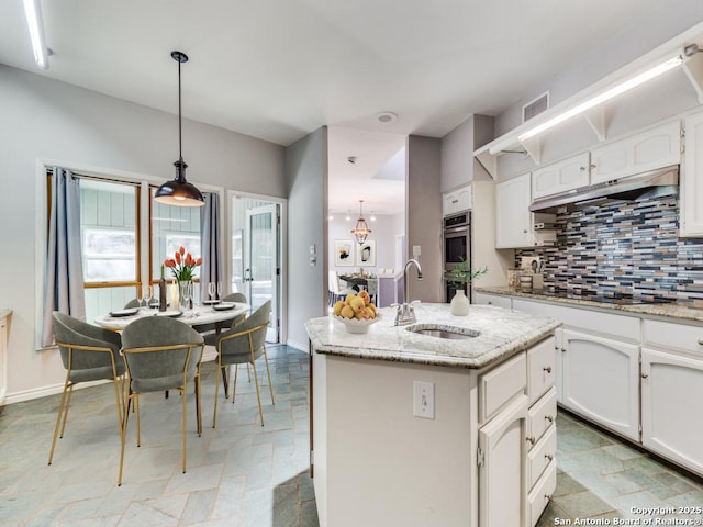 kitchen with sink, black cooktop, hanging light fixtures, a center island with sink, and white cabinets