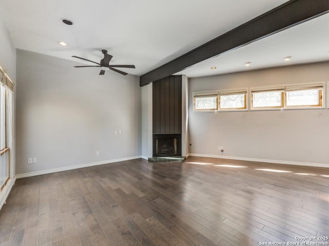 unfurnished living room with beamed ceiling, wood-type flooring, ceiling fan, and a fireplace