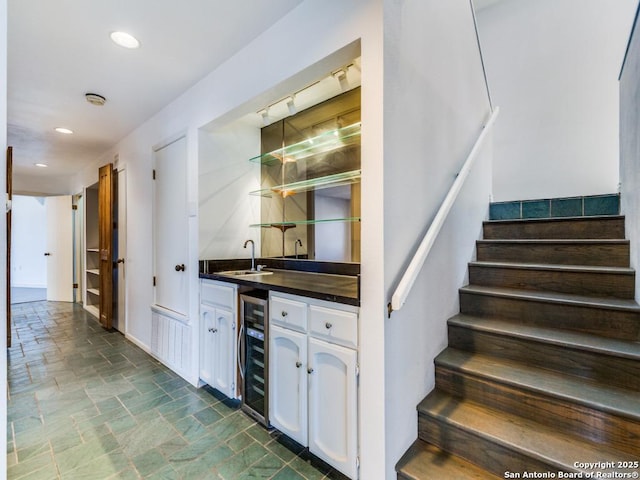 bar with beverage cooler, sink, and white cabinets