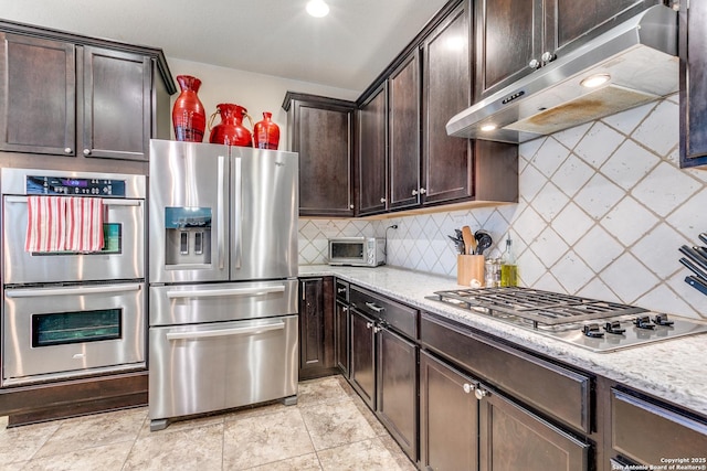 kitchen featuring dark brown cabinetry, light stone countertops, decorative backsplash, and stainless steel appliances