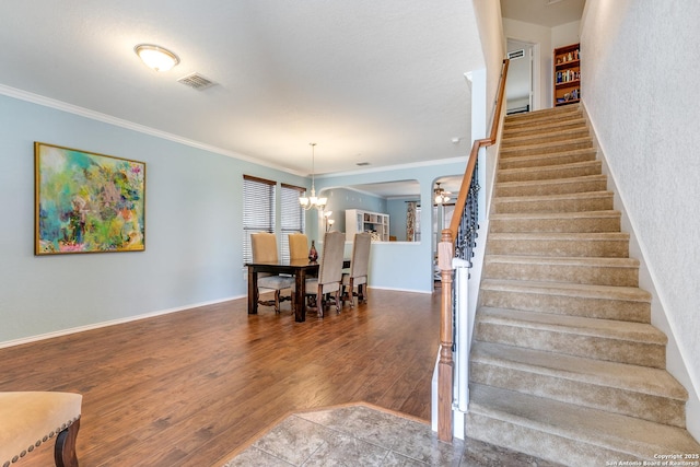 staircase with ornamental molding, a chandelier, and hardwood / wood-style floors