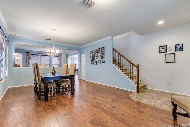 dining space featuring hardwood / wood-style flooring, ornamental molding, and a notable chandelier