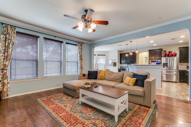 living room with dark wood-type flooring, ornamental molding, and ceiling fan