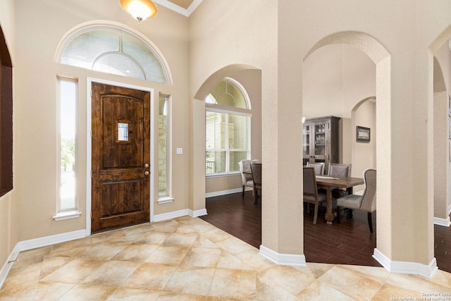 entryway featuring a towering ceiling and ornamental molding