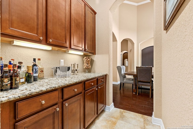 bar with ornamental molding and light stone countertops