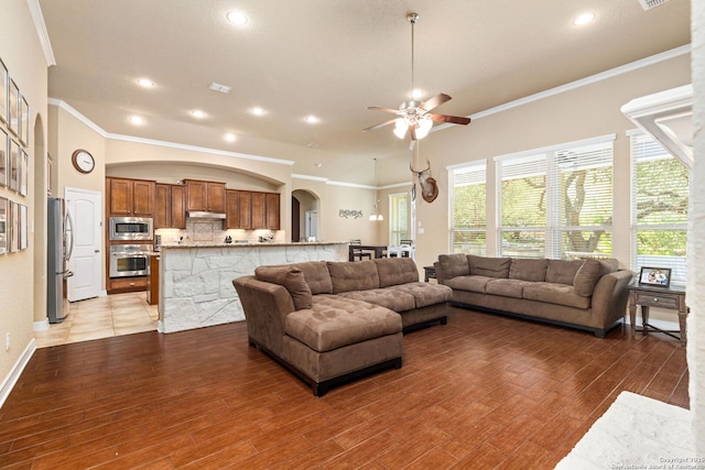 living room with wood-type flooring, crown molding, and ceiling fan