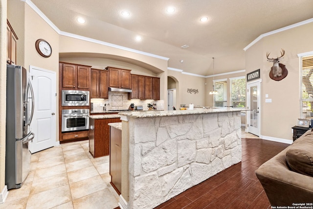 kitchen featuring light stone counters, stainless steel appliances, a center island with sink, and light hardwood / wood-style flooring