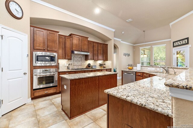 kitchen with sink, light stone counters, a center island, vaulted ceiling, and appliances with stainless steel finishes