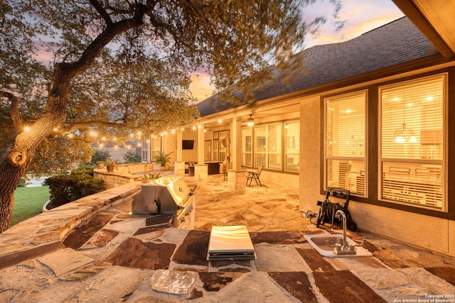 patio terrace at dusk with a grill and exterior kitchen