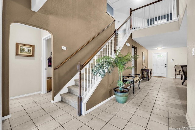 staircase with tile patterned flooring and a towering ceiling