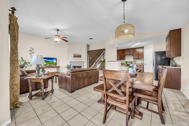 dining area featuring ceiling fan, a tile fireplace, and light tile patterned floors