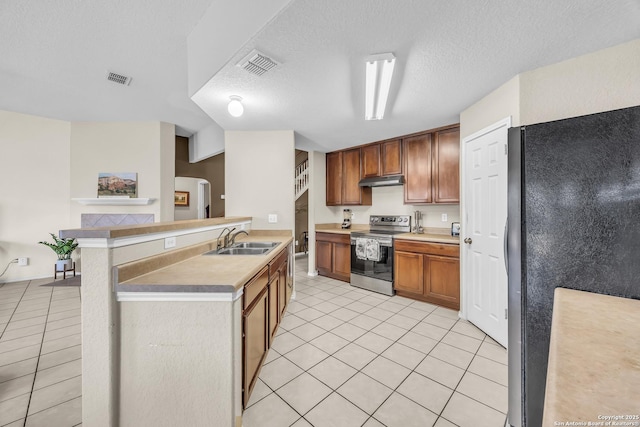 kitchen featuring sink, light tile patterned floors, stainless steel appliances, a textured ceiling, and kitchen peninsula