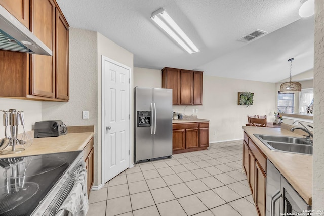 kitchen featuring sink, appliances with stainless steel finishes, a textured ceiling, decorative light fixtures, and exhaust hood