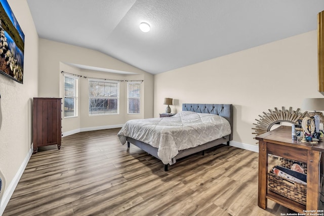 bedroom featuring hardwood / wood-style flooring, lofted ceiling, and a textured ceiling