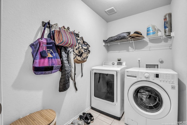 washroom with separate washer and dryer, light tile patterned floors, and a textured ceiling