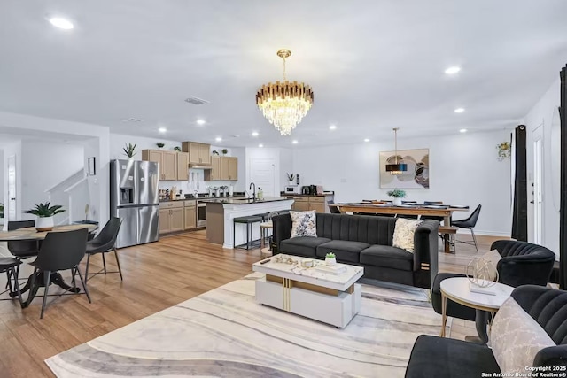 living room featuring sink, a chandelier, and light hardwood / wood-style floors