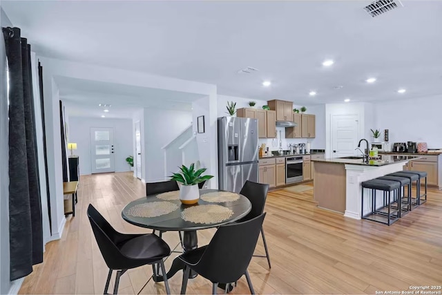 dining space with sink and light wood-type flooring