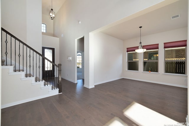 entryway with dark hardwood / wood-style floors and a towering ceiling