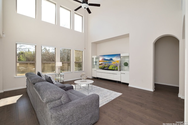 living room with a towering ceiling, a wealth of natural light, and dark hardwood / wood-style flooring